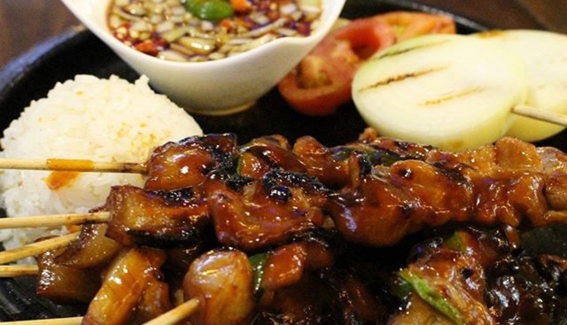 Pork BBQ skewers and rice on sizzling plate